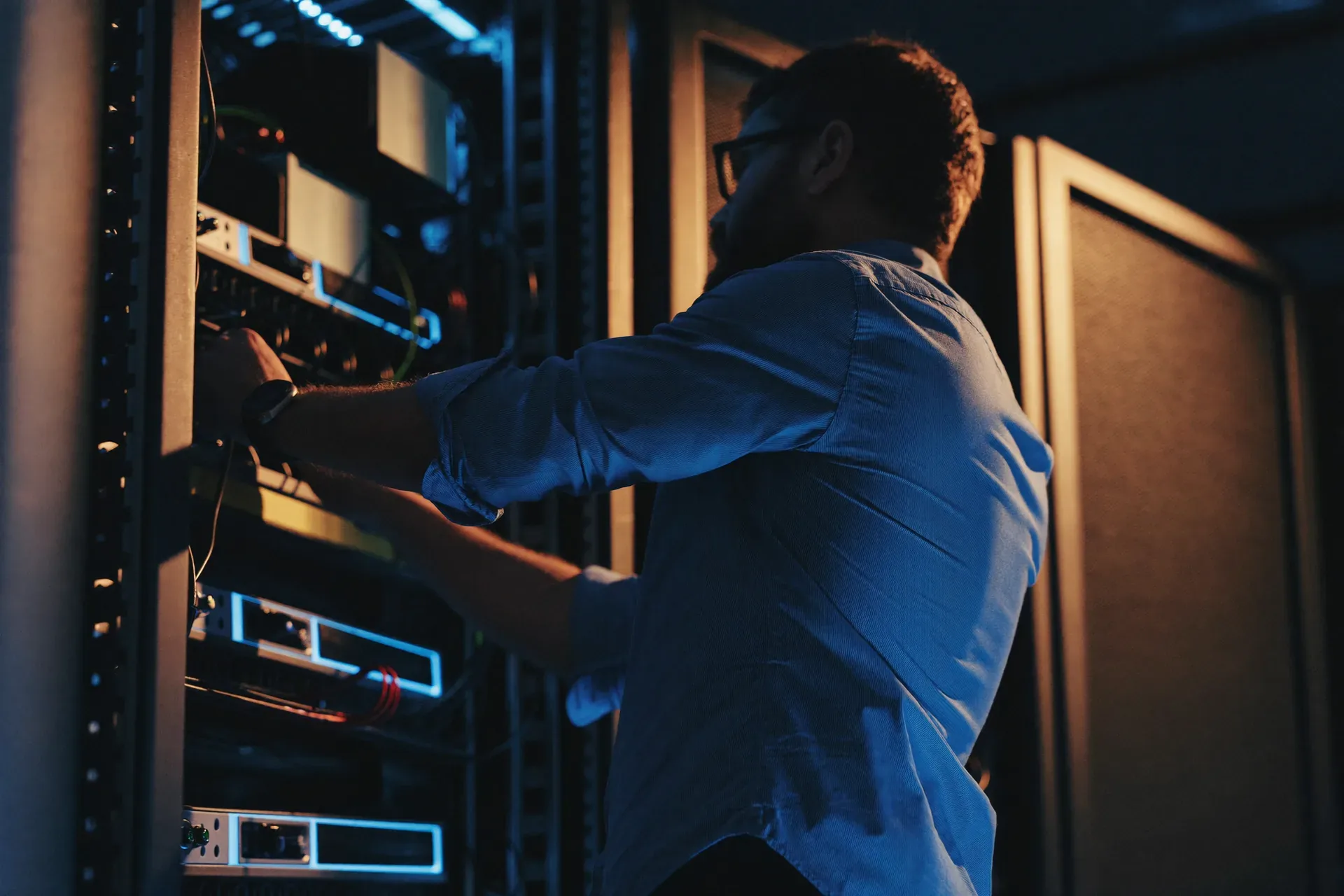 Technician working at server racks with blue LED lighting in a data centre